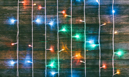 festive wooden background from old boards with a garland. with space for text. the concept of a new year, Christmas. tinted photoの写真素材