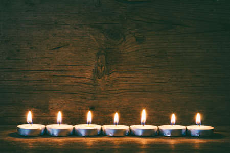 burning candles on the background of old barn boards, tinted photoの写真素材