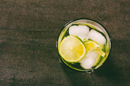 alcoholic cocktail with green lemon and ice close-up view from above, toning photo