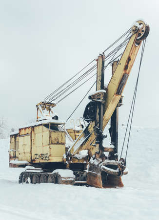 old yellow excavator in winter close up, tinted photoの写真素材
