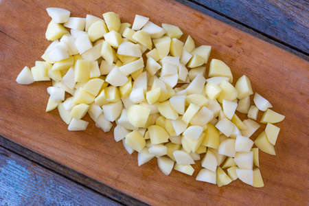 sliced raw potatoes on a cutting board on an old rustic wooden table. view from above close-upの写真素材