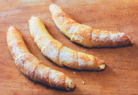 Three croissant on a wooden cutting board close-up view from above. toned photoの写真素材