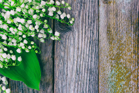 background of the old wooden barn boards with forest flowers, lilies of the valley. Tinted photo with space for textの写真素材