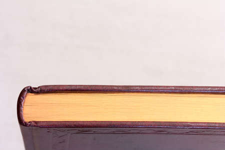 book with a gilt edge on the light grey background close-up view from above with space for your textの写真素材
