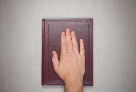 A man's palm on a book, an oath on the bible. Top view from aboveの写真素材