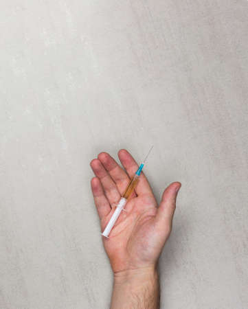 medical syringe with needle and drugs on the open men's palm on grey background, top view. mock up for text, phrases, letteringの写真素材
