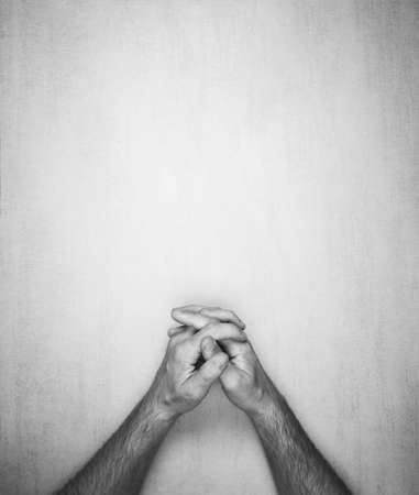 hands of a man are folded into a lock on a gray background, top view. black and white photo, mock up for text, phrases, letteringの写真素材