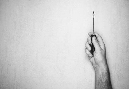 Screwdriver in a man's hand on a gray background, top view. black and white photo. mock up for text, phrases, letteringの写真素材