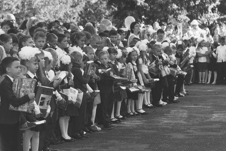 Adygea, Russia - September 1, 2017: children with bouquets of flowers enrolled in the first class with teachers on the school's solemn line in the day of knowledge, black and white photoのeditorial素材