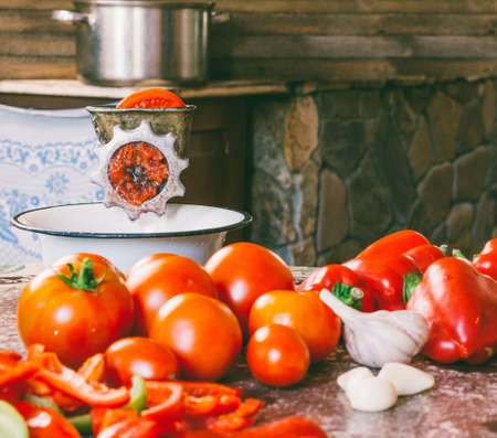 old vintage manual grinder and slices of fresh tomatoes, red bell pepper and garlic on the table for making homemade sauce, ketchupの写真素材