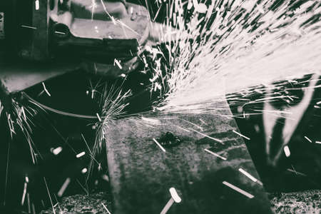 sparks flying from under the rotating disc grinder when cleaning steel parts after welding, black and white imageの写真素材