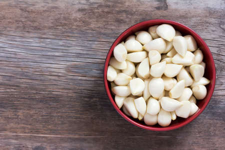 peeled cloves of garlic on an old wooden background closeup top view with space for textの写真素材