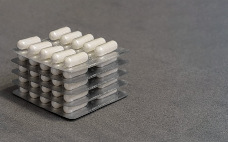 blisters with white gelatin capsules on a gray background with space for text