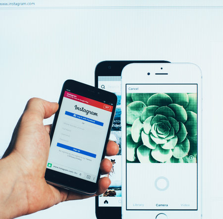 the registration page on the popular social network for sharing and rating photos and short videos Instagram on the screen of the Xiaomi smartphone and on the computer monitorのeditorial素材
