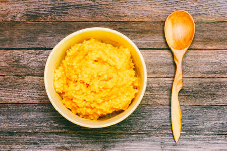 rice pumpkin porridge with milk and a wooden spoon on a wooden vintage grunge background top view close upの写真素材