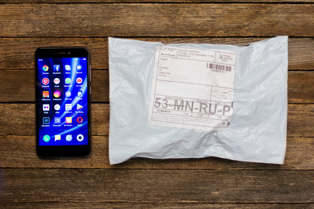 Adygea, Russia - January 24, 2018: Chinese smartphone xiaomi and parcel of the online store on a wooden tableのeditorial素材