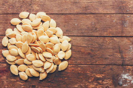 a bunch of pumpkin seeds on wooden retro grunge background, top view closeup with copy spaceの写真素材