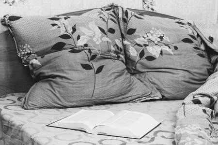 open book on a straightened bed close up, black and white photoの写真素材