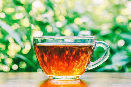 Cup of black tea on table on natural backgroundの写真素材