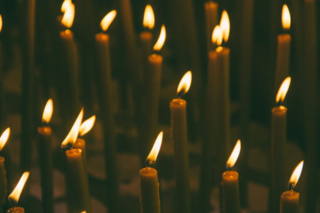 many burning wax candles in the temple
