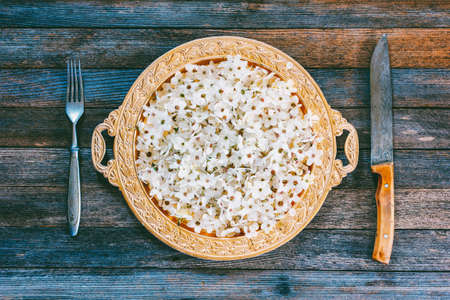 spring abstraction. fruit tree flowers in Golden dish, fork and knife on old wooden table, top view closeupの写真素材