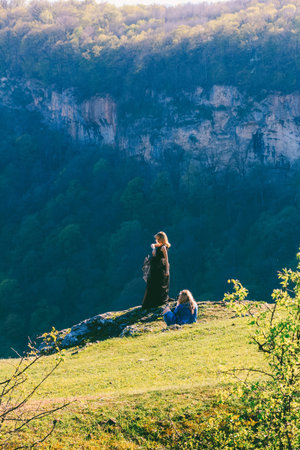 Adygea, Russia - April 15, 2018: girl photographer photographing a model in a black dress outdoors...