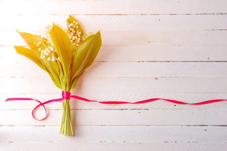 Lily flower bouquet tied with red ribbon on white wooden background with copy spaceの写真素材