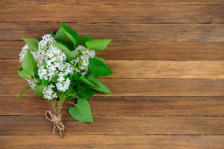 bouquet of white lilac flowers with green leaves on vintage wooden retro background with copy spaceの写真素材
