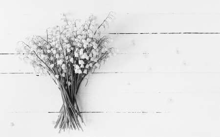 bouquet of lilies of the valley flowers closeup on white wooden table with copy space, black and white photoの写真素材