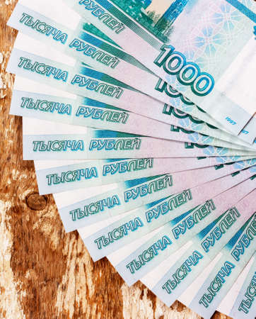 Russian banknotes in denominations of 1000 rubles are spread out on a fan on a wooden grunge backgroundの写真素材