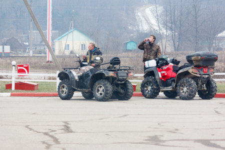 Adygea, Russia - December 20, 2015: Travelers on quad bikes rest and drink hot coffee in the...