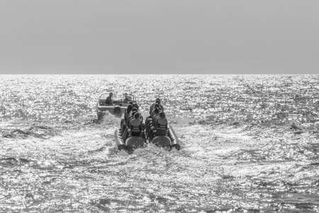 happy vacationers tourists ride an inflatable banana in the sea, black and white photoの写真素材