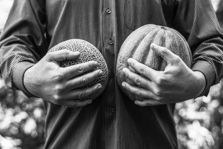 a man holding ripe melons of different varieties, black and white photoの写真素材