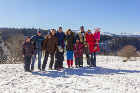 Adygea, Russia - January 23,  2017: a group of happy tourists with children on a background of snowy mountains on a Sunny winter dayのeditorial素材