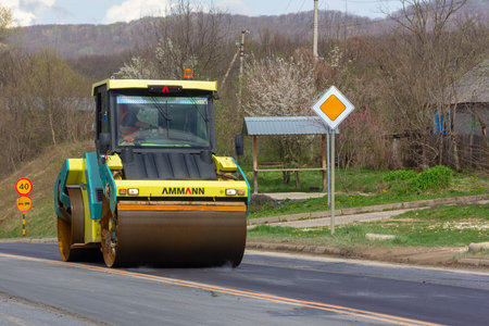 Kamennomostsky, Russia - April 13, 2019: asphalt compactor roller rolls new asphalt on the highway...