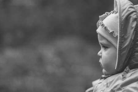 portrait of a serious pensive eleven month old baby girl on a natural background with copy space, black and white photoの写真素材