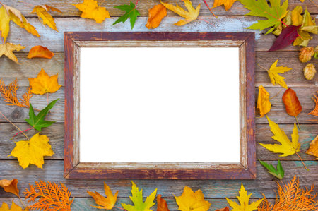 autumn composition, bright autumn leaves and picture frame on a wooden background with copy space....