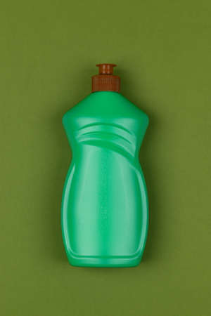 light green plastic bottle of dishwashing liquid on dark green background close-up top viewの写真素材