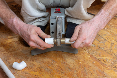 Work on the installation of heating or plumbing. Male plumber solders polypropylene plastic pipes...