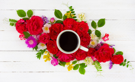 floral summer composition of roses, peonies, cornflowers, green leaves and a Cup of black coffee on...