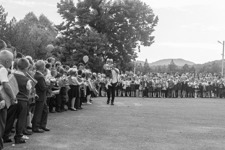 Adygea, Russia - September 1, 2018: school child with gifts, flowers and balloons in their hands and the teacher at the holiday knowledge day, black and white photographyのeditorial素材