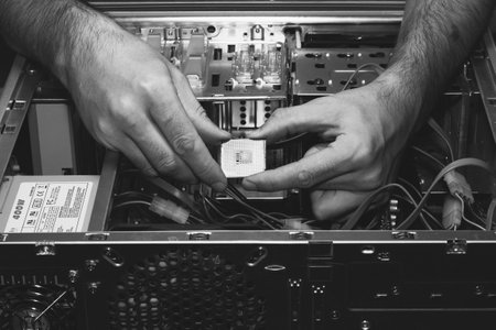 Maykop, Russia - September 17, 2016: Intel processor in men's hands on the background of the open system unit, black and white photoのeditorial素材