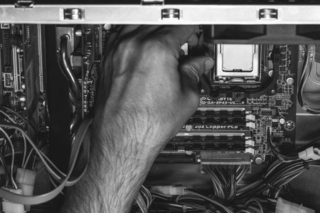 Maykop, Russia - September 17, 2016: male hand installs an Intel processor in the socket on the motherboard, black and white photoのeditorial素材