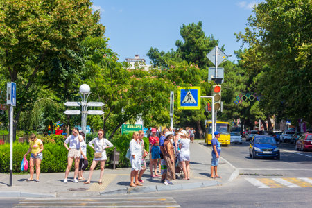 Anapa, Russia - August 12, 2019: a group of men and women stand at a traffic light in front of a pedestrian crossing on a Sunny summer dayのeditorial素材