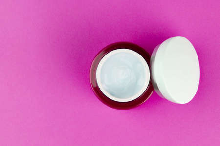 Pink jar with a light day moisturizing hyaluronic cream gel for the face on a pink background with a copy space top viewの写真素材