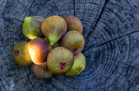a pile of figs on a wooden background with a copy of the space, a close-up view from above