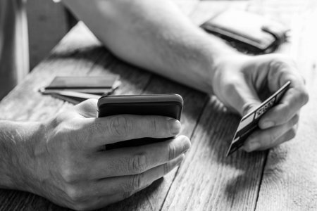 A man holds a credit card and uses a mobile phone close-up, payment for purchases in online stores,...