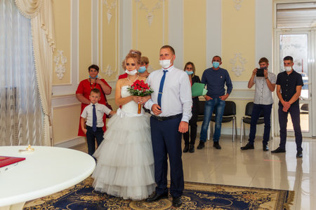 Maikop, Russia - October 16, 2020: The bride and groom and guests in medical masks during the wedding ceremony during the quarantine period and the coronavirus pandemic in the registry officeのeditorial素材