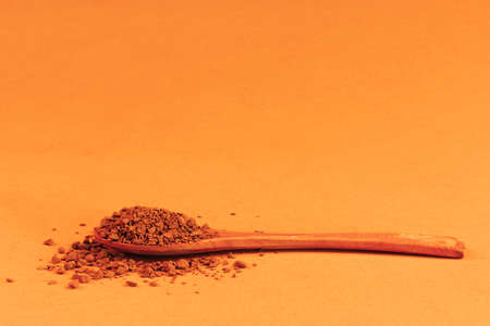 wooden spoon with instant granulated coffee on an orange yellow background with a copy spaceの写真素材