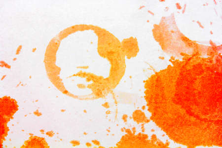 the round imprint of the glass of bright orange spots from spilled juice on a white backgroundの写真素材